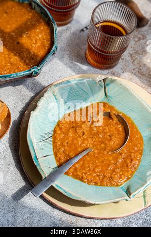 Un délicieux bol de soupe traditionnelle grecque aux lentilles, connue sous le nom de faux, magnifiquement servie dans la poterie artisanale. Le repas copieux est accompagné de pain frais Banque D'Images