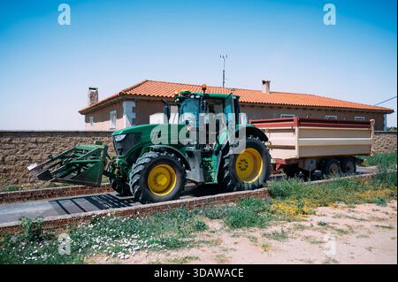 Un tracteur vert avec une grande remorque garée sur une ferme rurale à Guadalajara, Espagne. Le cadre agricole met en valeur le charme rustique du traditionnel Banque D'Images