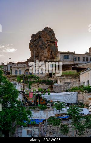 Ortahisar, Cappadoce, Turquie dispose d'une impressionnante formation rocheuse s'élevant au-dessus des bâtiments traditionnels en pierre avec un feuillage vert, créant un superbe c Banque D'Images