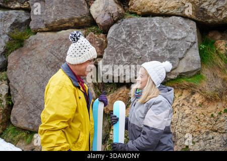 Un couple plus âgé, vêtu chaudement de vêtements d’hiver, partage un moment joyeux en se préparant au ski. Leur bonheur est évident lorsqu'ils embrassent le Banque D'Images