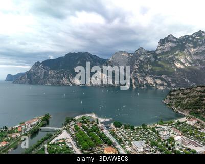 Vue aérienne d'une ville pittoresque au bord du lac nichée dans le cadre spectaculaire de montagnes imposantes. L'eau tranquille est parsemée de bateaux en dessous Banque D'Images