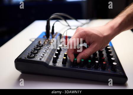 Les doigts tactiles manipulent les cadrans lumineux lors de la configuration de SoundCheck, un technicien professionnel règle l'équipement audio avec plusieurs câbles connectés Banque D'Images