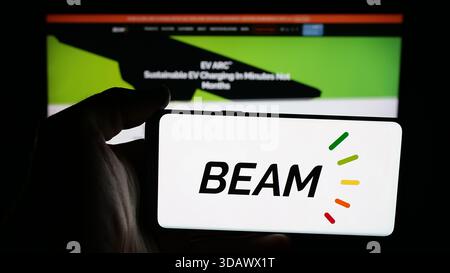Stuttgart, Allemagne - 12-02-2025 : personne tenant un téléphone portable avec le logo de la société américaine de recharge de véhicules électriques Beam Global sur l'écran devant la page Web. Banque D'Images