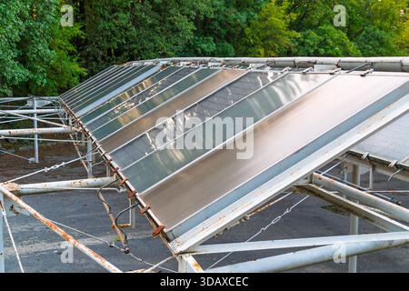Vieux capteurs solaires plats usés montés sur un cadre en métal rouillé. Banque D'Images