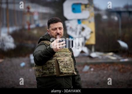 Kupyansk, Ukraine. 12 décembre 2025. Le président ukrainien Volodymyr Zelenskyy, prend un selfie devant le panneau envolé par balles pour Kupyansk lors d’une visite sur les lignes de front de la région de Kharkiv, le 12 décembre 2025, à Kupyansk, dans l’oblast de Kharkiv, Ukraine. Le président russe Poutine a affirmé que la ville était sous contrôle russe. Crédit : Pool photo/Bureau de presse présidentiel ukrainien/Alamy Live News Banque D'Images