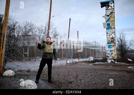 Kupyansk, Ukraine. 12 décembre 2025. Le président ukrainien Volodymyr Zelenskyy, prend un selfie devant le panneau envolé par balles pour Kupyansk lors d’une visite sur les lignes de front de la région de Kharkiv, le 12 décembre 2025, à Kupyansk, dans l’oblast de Kharkiv, Ukraine. Le président russe Poutine a affirmé que la ville était sous contrôle russe. Crédit : Pool photo/Bureau de presse présidentiel ukrainien/Alamy Live News Banque D'Images