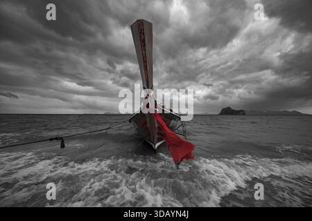 Bateau à longue queue sur la plage avec des nuages de pluie sombres derrière elle, île de Koh Ngai, mer d'Andaman, province de Satun, sud de la Thaïlande, Thaïlande Banque D'Images