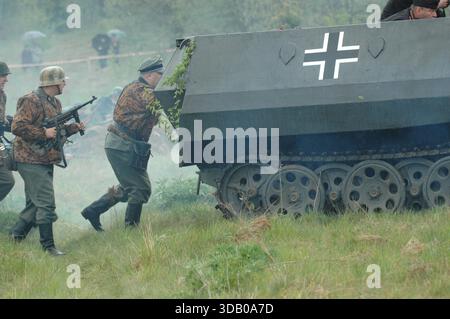 Infanterie allemande de la Wehrmacht avançant aux côtés de véhicules blindés pendant la reconstitution de la seconde Guerre mondiale, Sanok, Pologne. Banque D'Images