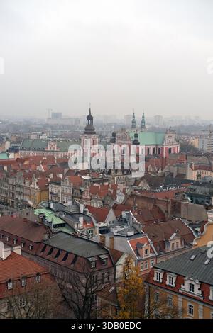 Composition verticale montrant les Poznań toits de la vieille ville et les tours de la cathédrale, les carreaux rouges denses, les façades pastel, la ville lointaine adoucie par la brume. Banque D'Images