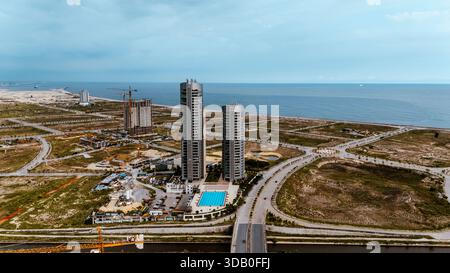 Vue aérienne de gratte-ciel étincelants perçant la ligne d'horizon au-dessus de la piscine bleue tranquille, contre le paysage sablonneux, Eko Atlantic, LAGOS Banque D'Images