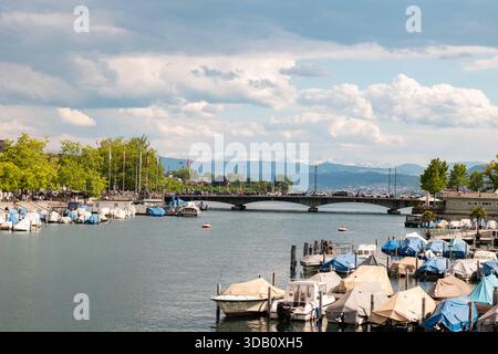 Vue vers le pont du Quai sur la rivière Limmat à Zurich, Suisse, bateaux à moteur et voiliers sur le quai. Zurich, Suisse- 17 mai 2025 : vue vers le pont du quai sur la rivière Limmat, bateaux à moteur et voiliers sur le quai, les gens marchant le long de la promenade du front de mer et traversant le pont. Bâtiments en arrière-plan à gauche, été, jour nuageux. Edit switzerland zurich B97A8285 Banque D'Images