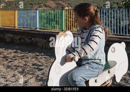 Jeux amusants : un enfant sur un jouet printanier coloré en forme de lapin ou de lapin Banque D'Images