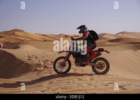Motocycliste hors route à travers les dunes de sable dans le désert algérien Banque D'Images