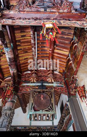Des sculptures en bois complexes et un tambour rituel traditionnel (fǎgǔ) suspendu au plafond en caisson orné (zǎojǐng) d'un temple taïwanais historique. Banque D'Images