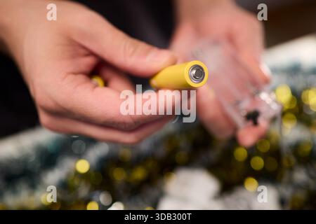 Technicien assemblant le jeu de lumières festives, vue rapprochée des mains installant l'éclairage des fêtes, se concentrer sur le technicien connectant le jeu de lumières pendant Banque D'Images