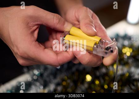 Technicien assemblant le jeu de lumières festives, vue rapprochée des mains installant l'éclairage des fêtes, se concentrer sur le technicien connectant le jeu de lumières pendant Banque D'Images