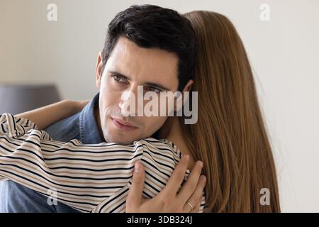 Jeune homme inquiet embrassant la femme, gros plan Banque D'Images