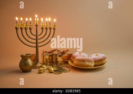 Configuration de célébration Hanukkah. Une menorah, des dreidels, des coffrets cadeaux et des beignets sur fond beige Banque D'Images