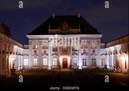 Palais en cuivre illuminé (Pałac Pod Blachą) la nuit, architecture baroque élégante avec façade symétrique et éclairage spectaculaire. Banque D'Images