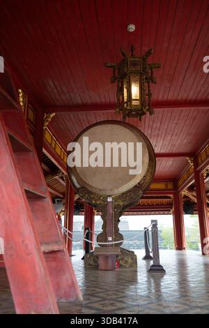 Un grand tambour traditionnel se dresse majestueusement dans un temple asiatique richement décoré, avec du bois rouge vif, des accents d'or complexes, et un historique Banque D'Images