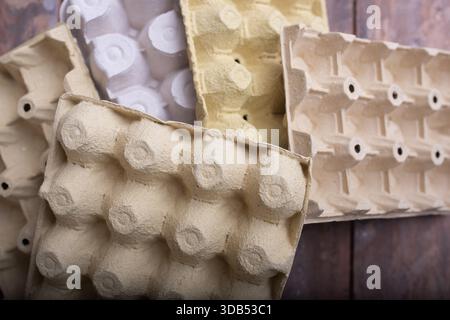 Collection de cartons d'oeufs de différentes couleurs et textures, fabriqués à partir de matériaux recyclés, affichés sur une surface en bois rustique, mettant en évidence p durable Banque D'Images