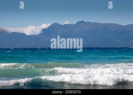 Mer Ionienne avec des vagues spectaculaires pendant une journée d'été tardive. Montagnes albanaises en arrière-plan. Ciel bleu avec des nuages blancs. Nord de l'île Corfou ( Banque D'Images