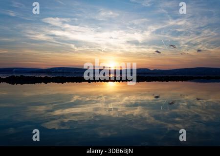 Un magnifique coucher de soleil sur le lac Balaton, avec le ciel reflété dans l'eau calme. Banque D'Images