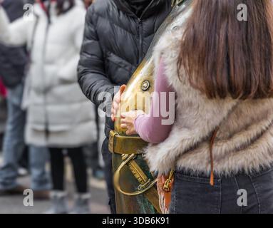 Gros plan d'un homme et d'une femme en vêtements d'hiver touchant la célèbre statue en laiton 'Golden Carp' au marché de Noël festif de l'Avent Bazilika Banque D'Images