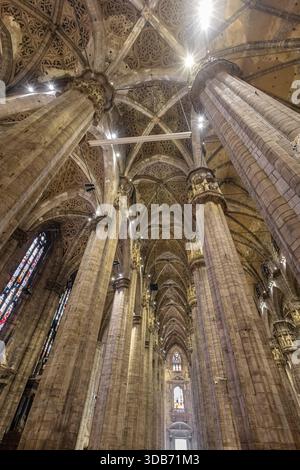 Un superbe intérieur gothique de cathédrale avec d'imposantes colonnes de pierre, des voûtes complexes et des vitraux colorés. L'architecture dramatique transmet Banque D'Images