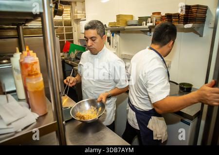 Cuisiniers préparant des aliments dans une cuisine de restaurant Banque D'Images