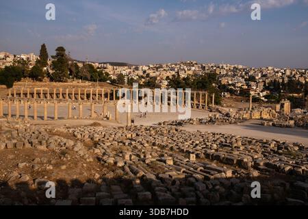 La place ovale et la colonnade de Jerash, en Jordanie, sont vues d'en haut, avec des ruines antiques au premier plan et la ville moderne qui s'étend à travers le hi Banque D'Images