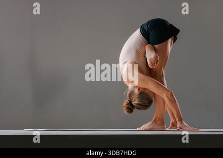 Femme en forme faisant le pont Pilates avec lifting des jambes, core et fessier entraînement sur tapis à l'intérieur. Banque D'Images