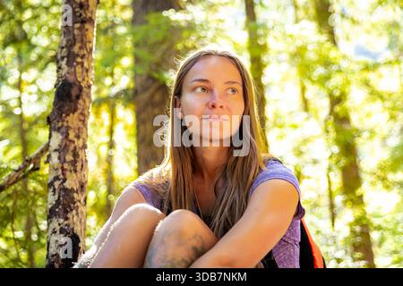 Une belle femme est capturée dans un portrait en gros plan, appréciant clairement la beauté sereine de la nature forestière. Banque D'Images