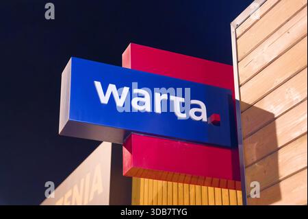 Warta compagnie d'assurance signe sur l'extérieur du bâtiment, bleu et rouge marque de l'assureur polonais bien connu photographié la nuit. Banque D'Images