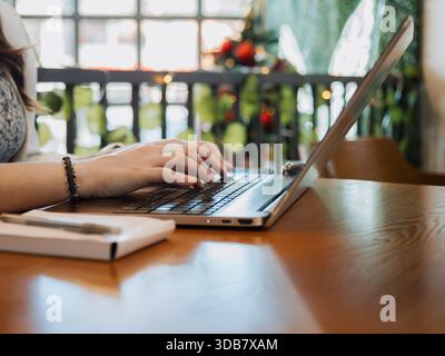 Gros plan des mains à l'aide d'un ordinateur portable sur un bureau avec ordinateur portable à proximité. Travail, étude et concept de productivité en ligne. Banque D'Images