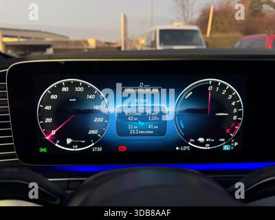 Écran numérique à l'intérieur d'un tableau de bord de voiture montrant la vitesse, la puissance et la charge pour un véhicule hybride Banque D'Images