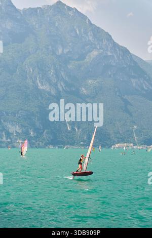 Planches à voile sur le lac de Garde photographiées depuis Torbole sul Garda. Riva del Garda en arrière-plan. Banque D'Images