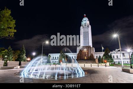 Vue nocturne du Capitole de l'État du Nebraska à Lincoln, États-Unis. Limestone Tower of the Plains présente un dôme doré et une statue de Sower derrière des fontaines illuminées Banque D'Images