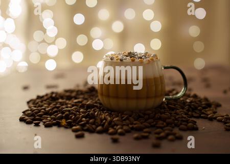 une scène de café confortable avec un latte superposé avec des garnitures festives, entouré de grains de café éparpillés sur fond de lumières bokeh chaudes, cre Banque D'Images