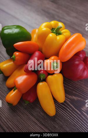un assortiment vibrant de poivrons colorés disposés sur une surface en bois texturé, présentant des teintes et des formes variées avec un contraste vif et natura Banque D'Images