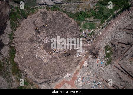 Vue aérienne d'une énorme décharge avec des bulldozers dispersés travaillant au milieu de tas de déchets, Dhaka, Division de Dhaka, Bangladesh. Banque D'Images