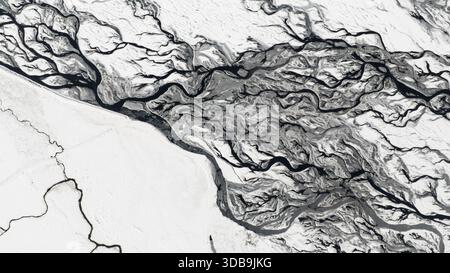 Vue aérienne des rivières glaciaires sculptant à travers un paysage blanc et sombre, leurs vrilles sombres créant un contraste fascinant, l'Islande. Banque D'Images