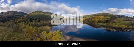 Vue aérienne des eaux tranquilles et sombres du Loch Lubnaig reflétant le ciel et les collines environnantes recouvertes de teintes dorées et vertes de l'automne, Callander, Écossais Banque D'Images