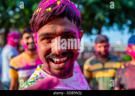 Homme souriant avec le visage couvert de poudres colorées pendant le festival Holi, en Inde – célébrant la joie, la tradition et les couleurs vibrantes de la culture indienne. Banque D'Images