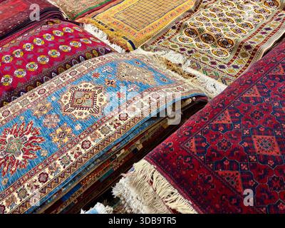 Tapis et tapis traditionnels d'Asie centrale richement colorés empilés à vendre Banque D'Images