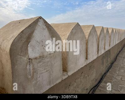 Gros plan de créneaux fendus en flèche sur un mur de forteresse plâtré. Banque D'Images