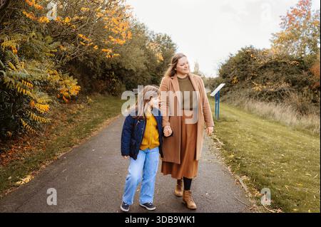 Mère et fille marchant ensemble sur un chemin d'automne dans le parc Banque D'Images