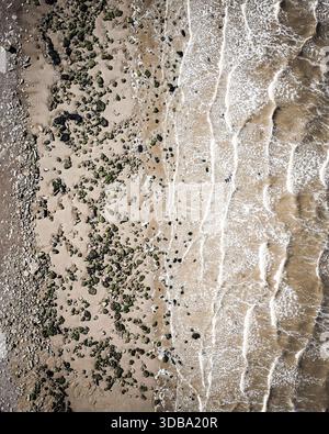 Vue aérienne du point de rencontre de la plage de sable et des vagues douces, la côte de Camber Sands, Camber Sands, Angleterre, Royaume-Uni. Banque D'Images