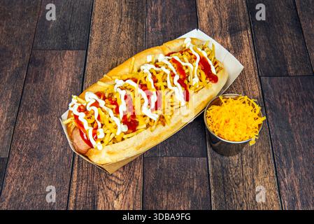 Un hot dog américain classique servi dans un petit pain moelleux, avec une saucisse grillée, garnie de moutarde jaune, ketchup, oignon coupé en dés et ​​pickles tranché Banque D'Images