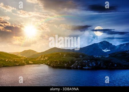 lac alpin serein parmi les collines verdoyantes. concept de changement de jour et de nuit. beau paysage d'été avec le ciel magnifique sur les sommets de montagne avec le soleil et Banque D'Images